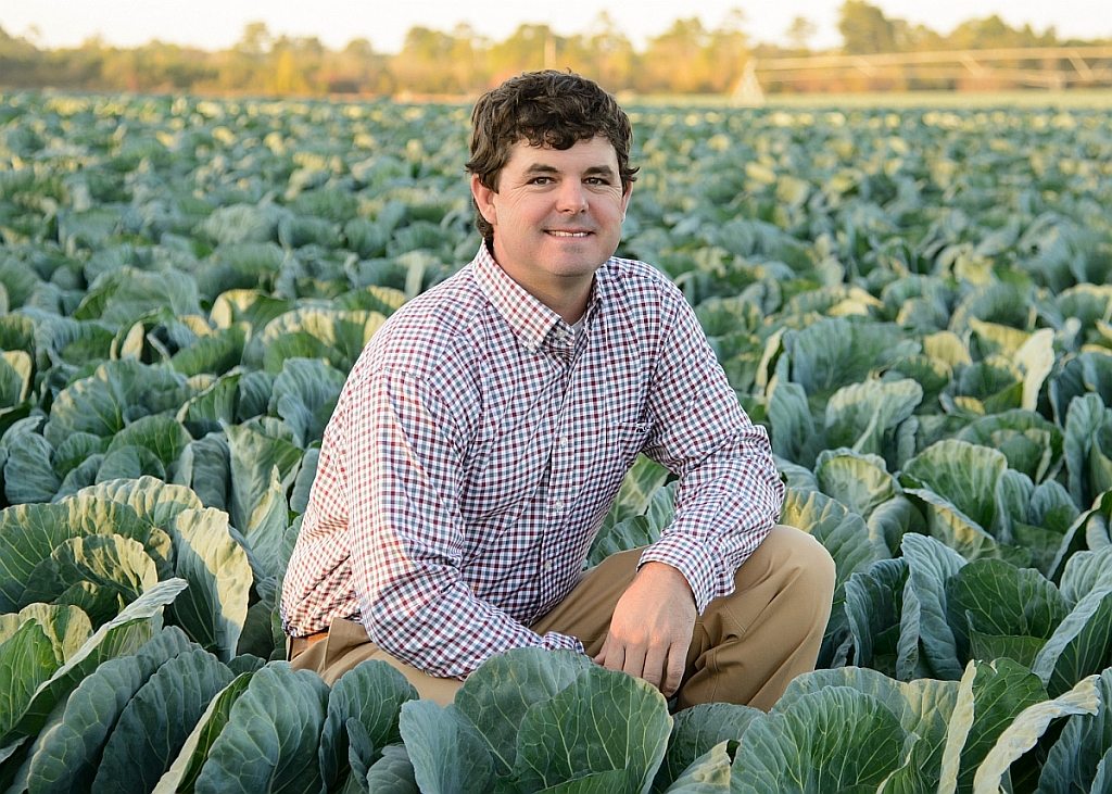UGA Alumnus Sam Watson surrounded by a field of cabbage
