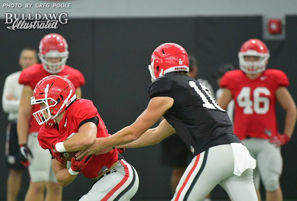 Jacob Eason (10) hands the ball off to one of the running backs