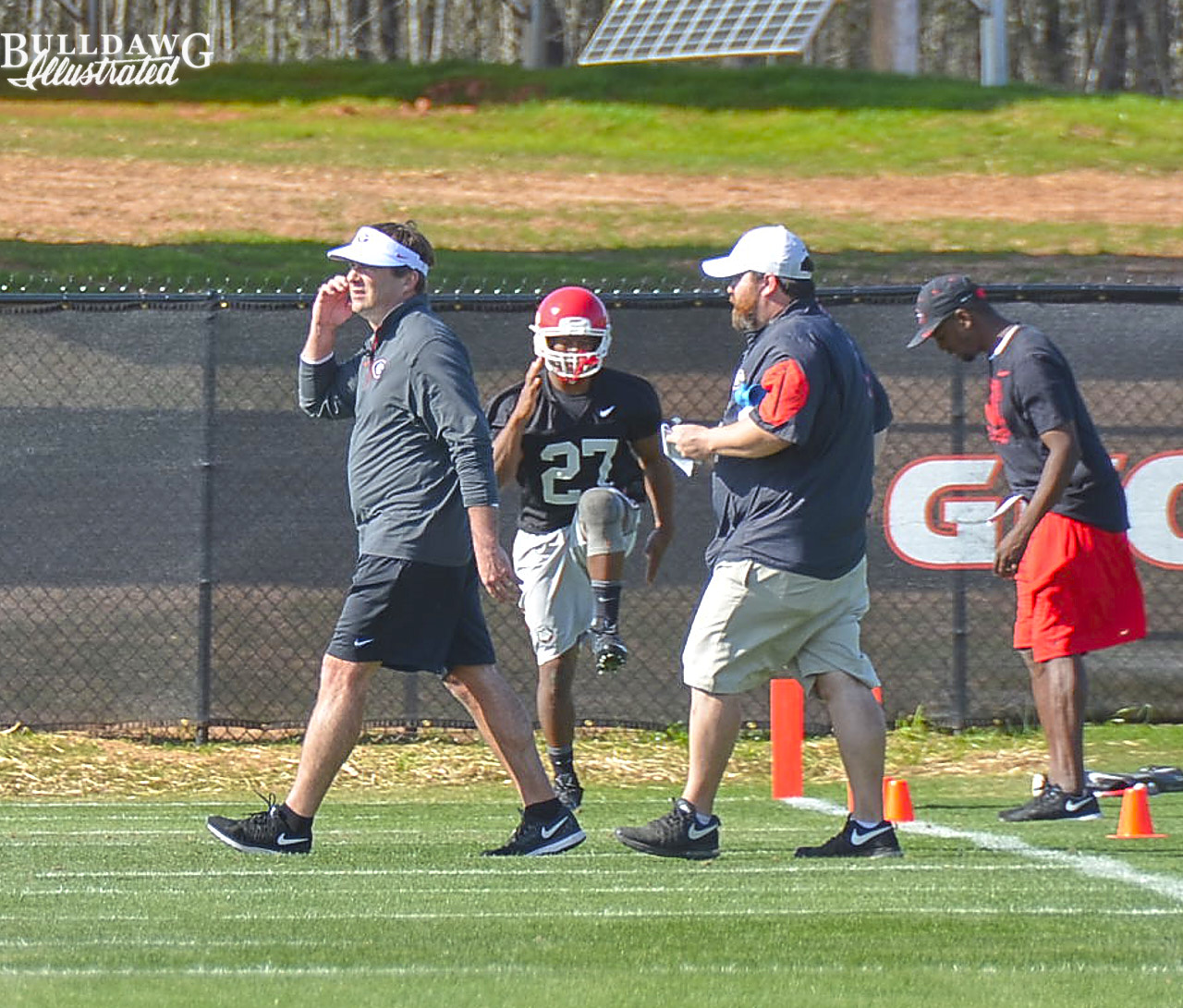 Kirby Smart takes a call while Nick Chubb works out