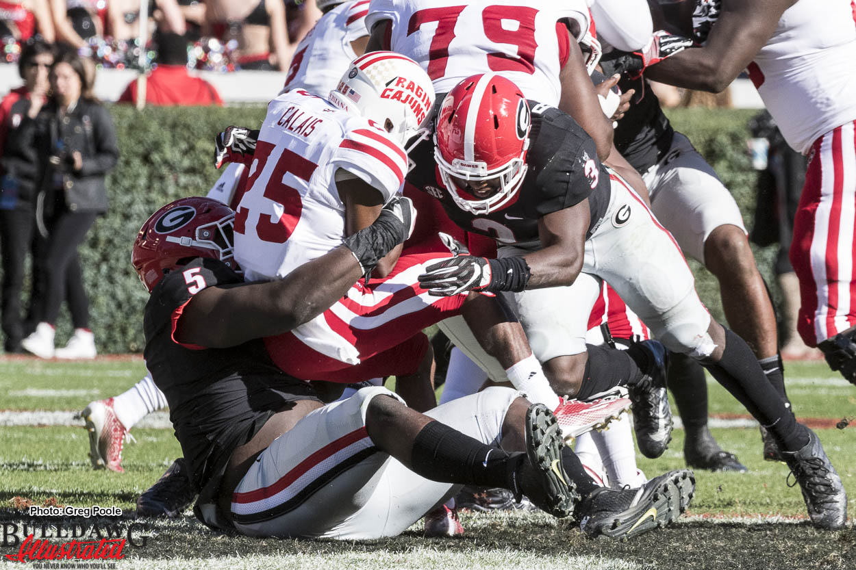 Julian Rochester (5) and Roquan Smith (3) tackle ULL RB Raymond Calais (25)